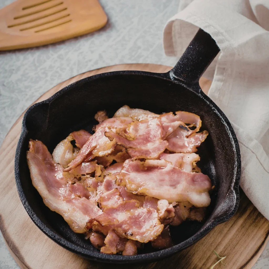 Pedaços de bacon fritando em uma panela de ferro